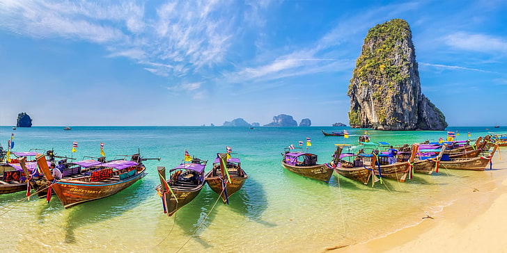 Several boats are docked along the sandy beach