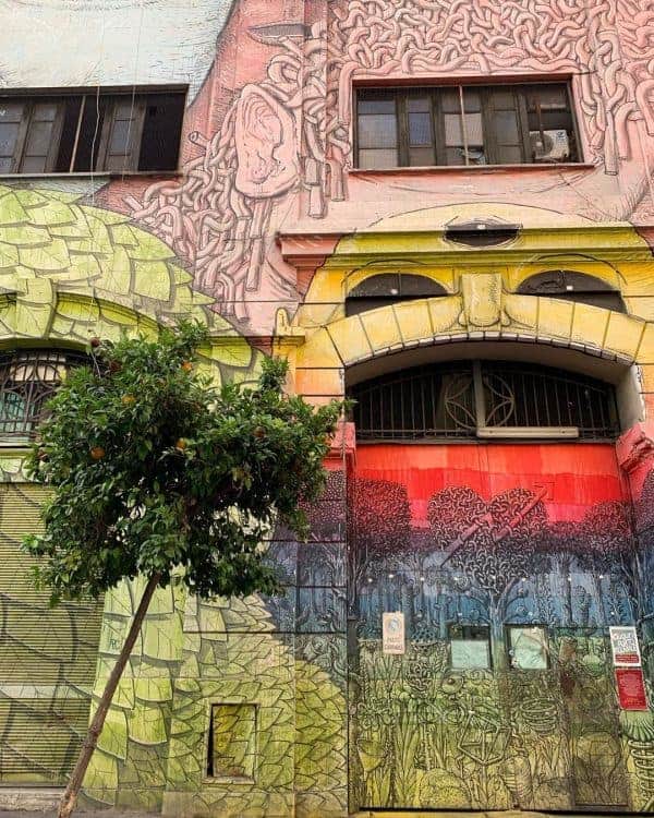 A strikingly colorful building in Rome is enhanced by a verdant tree in front