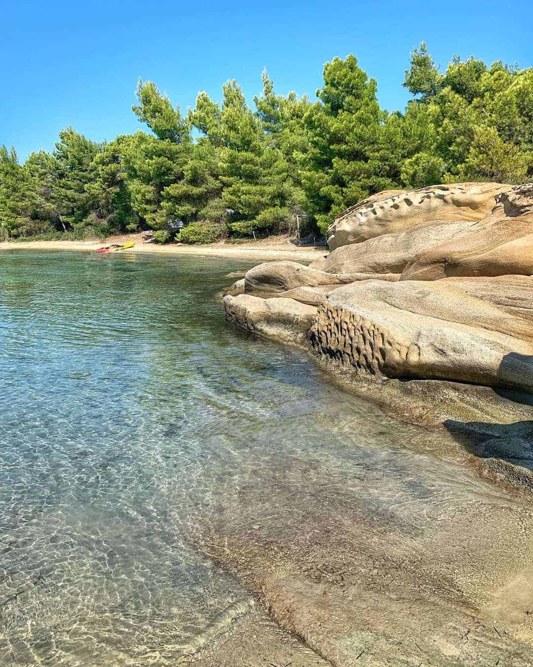 A scenic beach featuring rocks and trees lining the shore