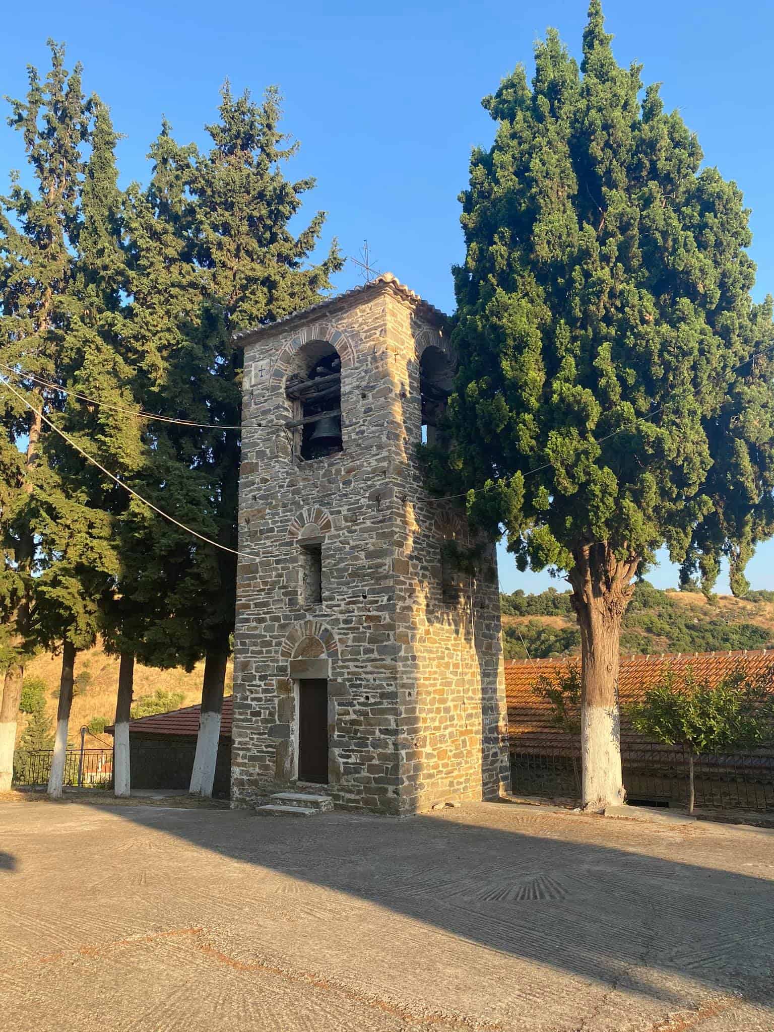 A stone tower featuring a prominent bell at its summit