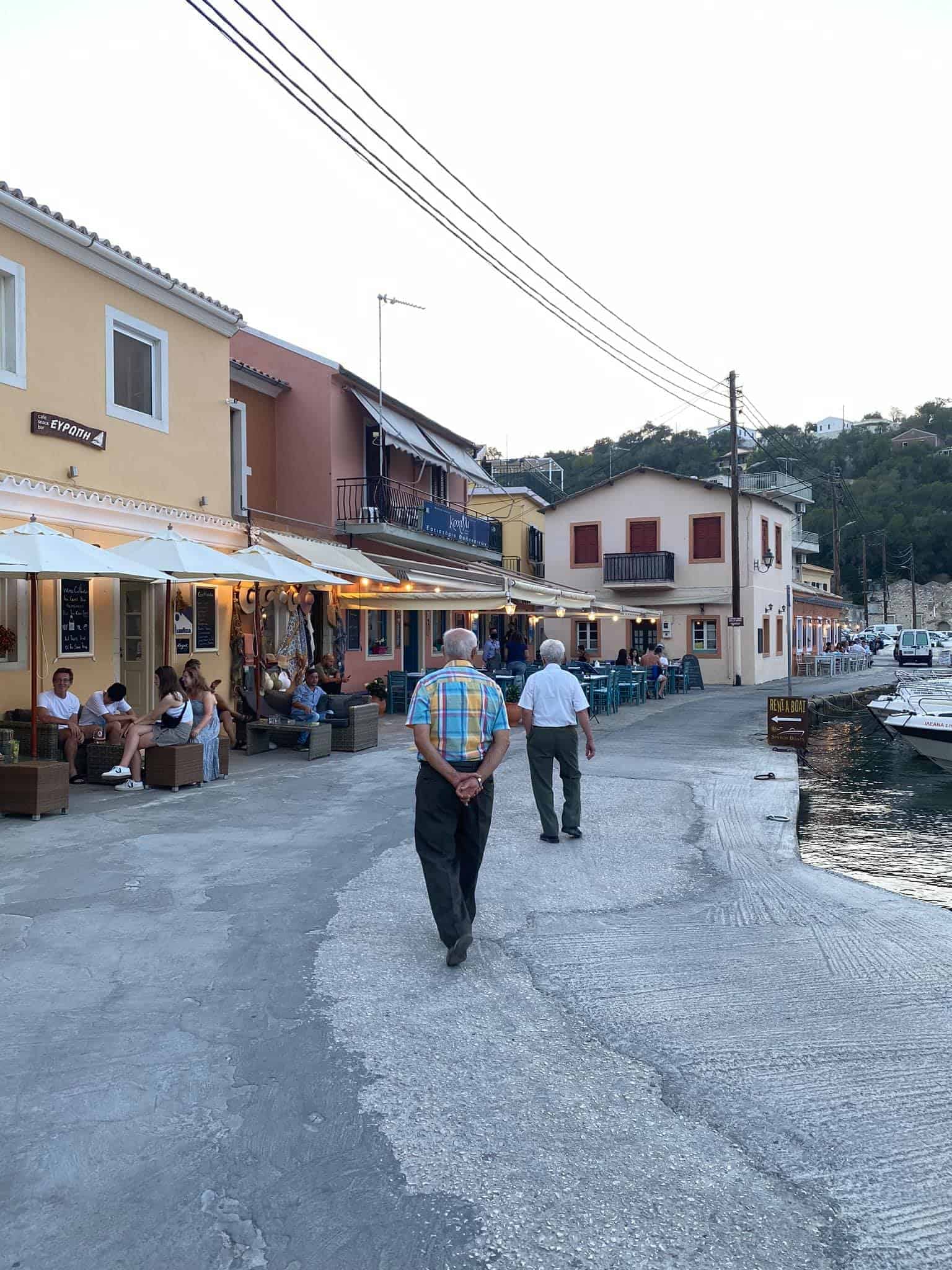 A man walks leisurely down a street by a marina