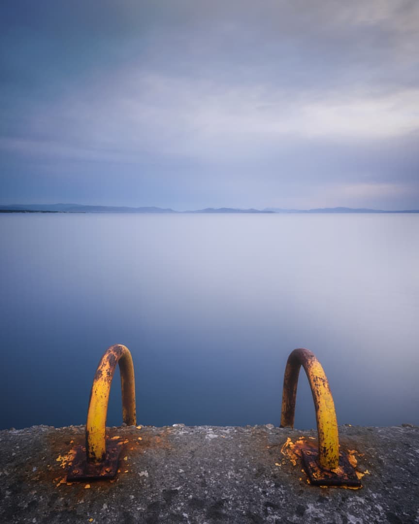 Two yellow metal bars positioned at the water's edge