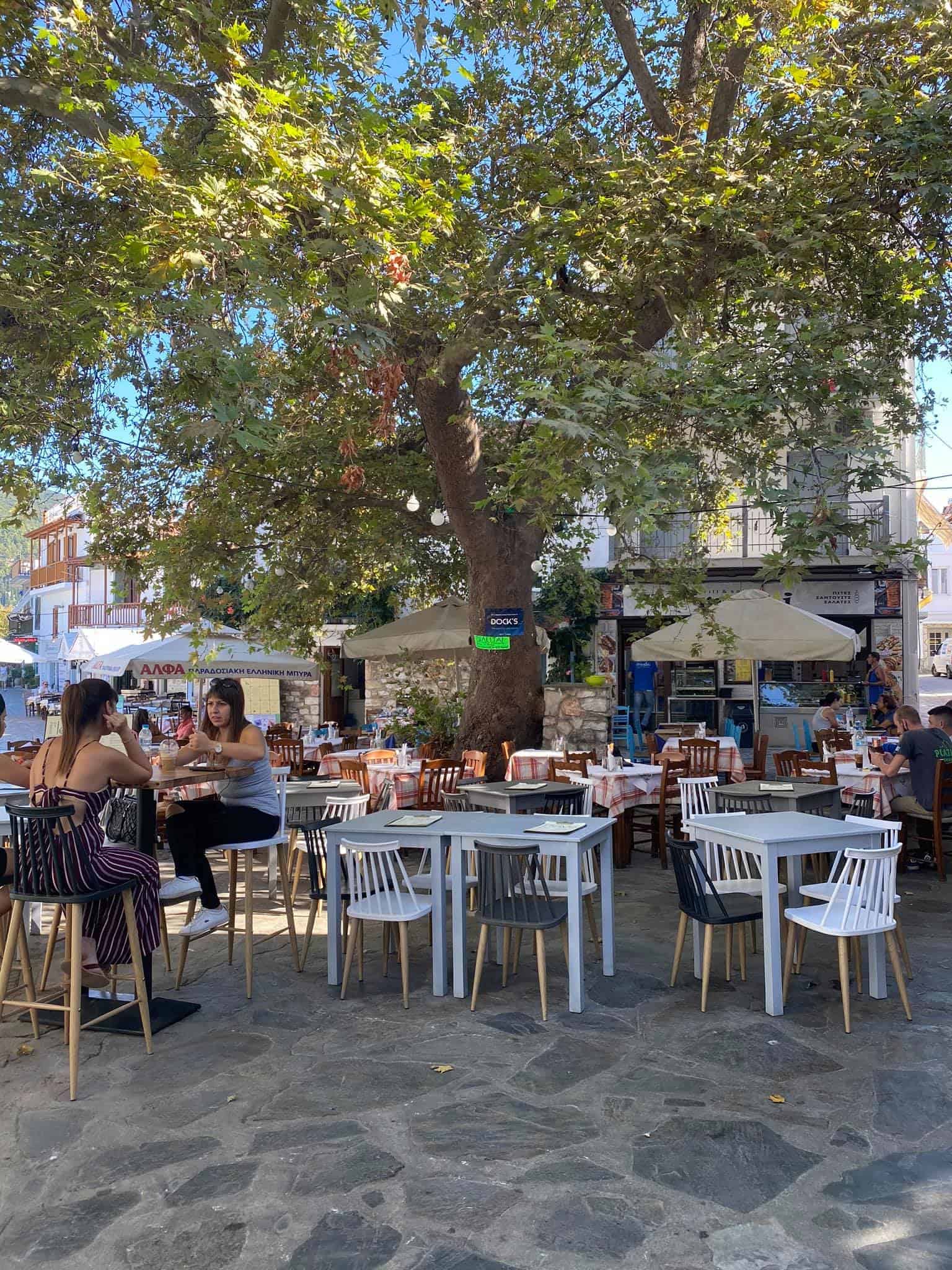 A lively outdoor café scene featuring people seated at tables