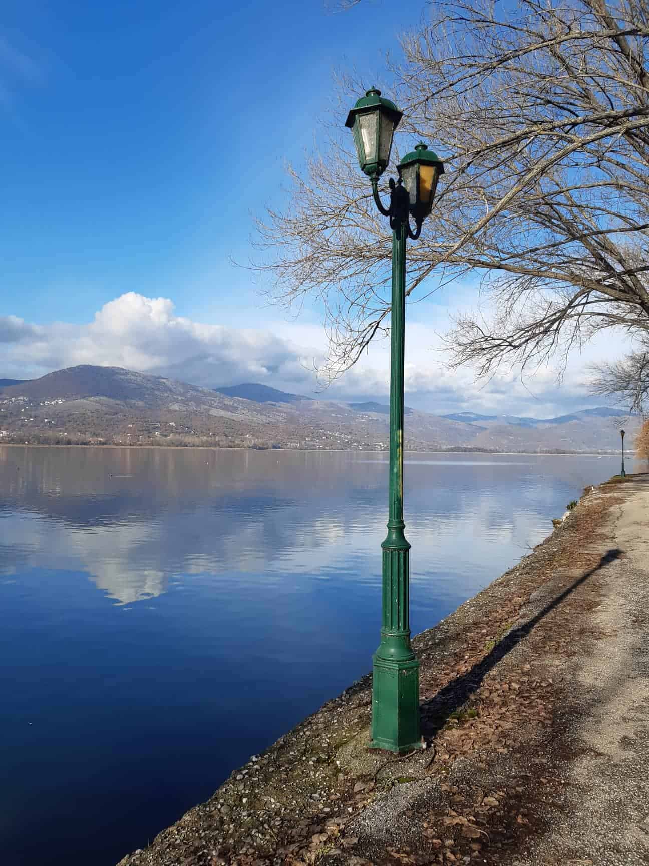 A street light stands beside a tranquil lake