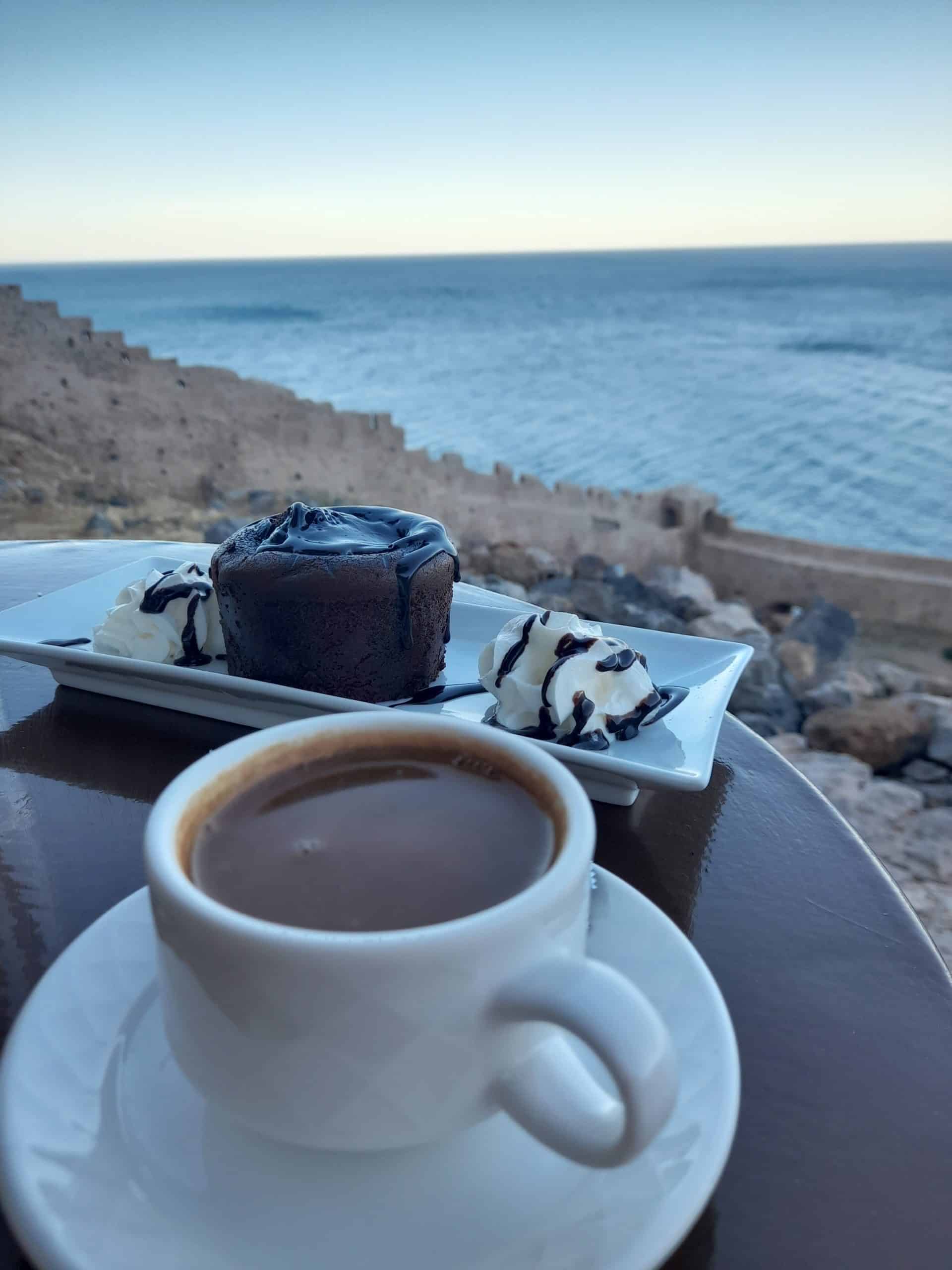 A serene beach scene featuring a cup of coffee and a delectable dessert on a table