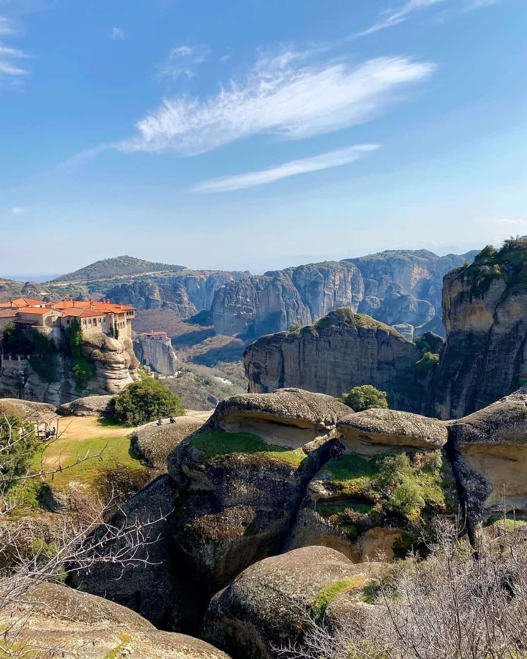 A breathtaking view of Meteora's towering rock formations and monasteries set against a clear blue sky in Greece