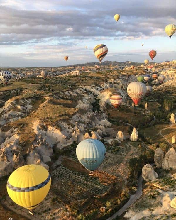 Colorful hot air balloons ascend above a scenic valley