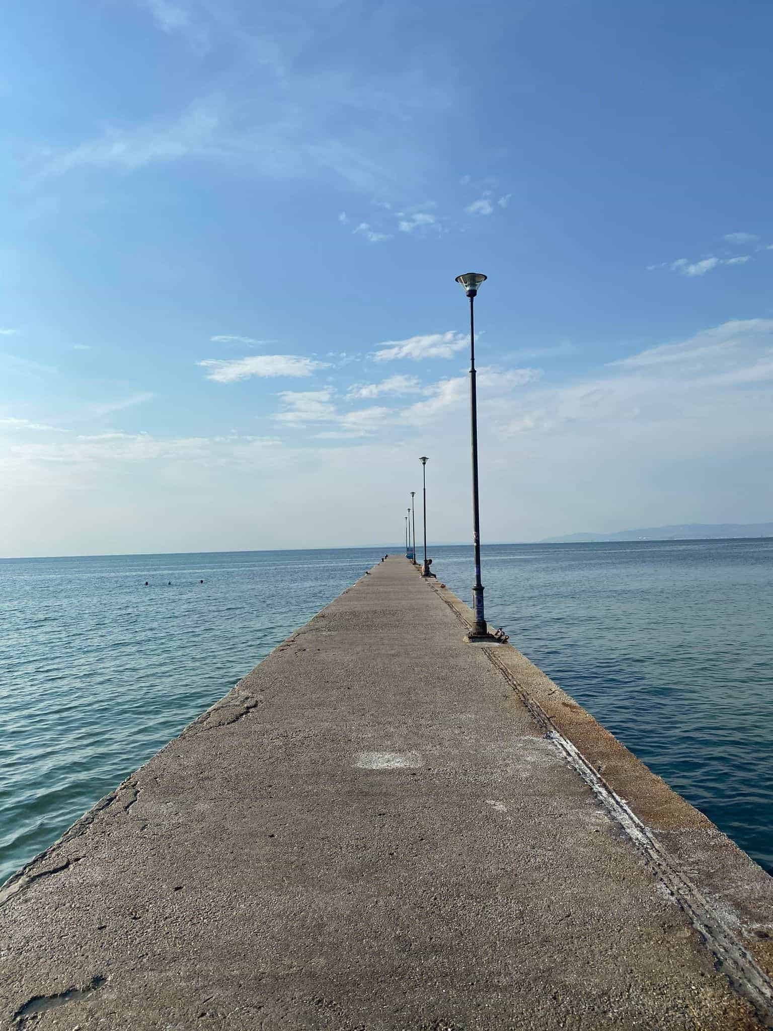 A serene view of a long pier leading to a light post at the end