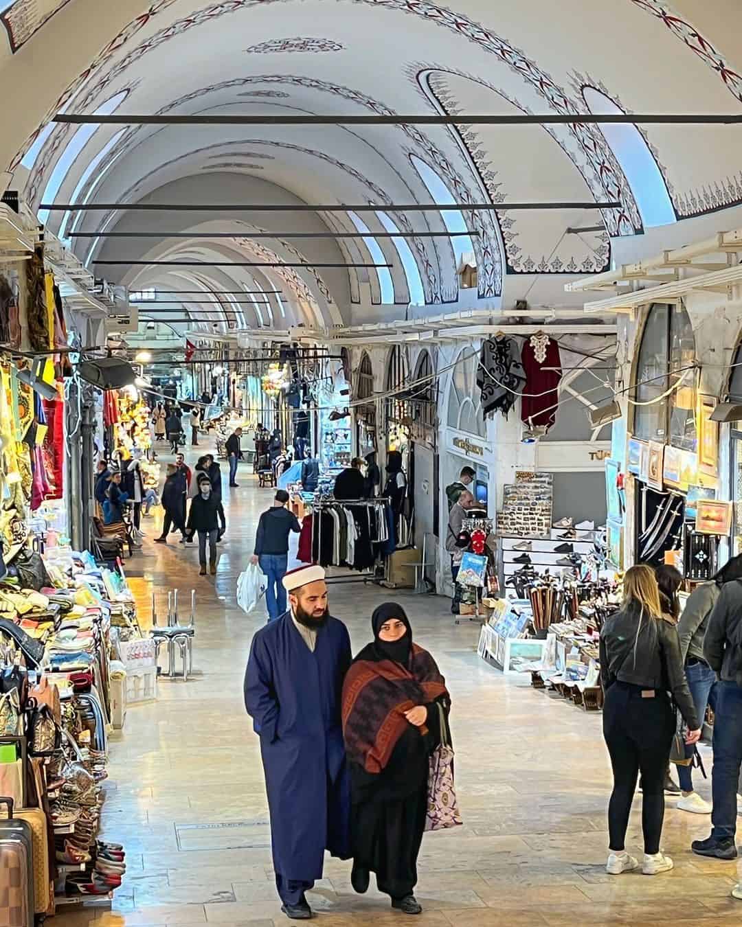 A man and woman stroll through a vibrant indoor market