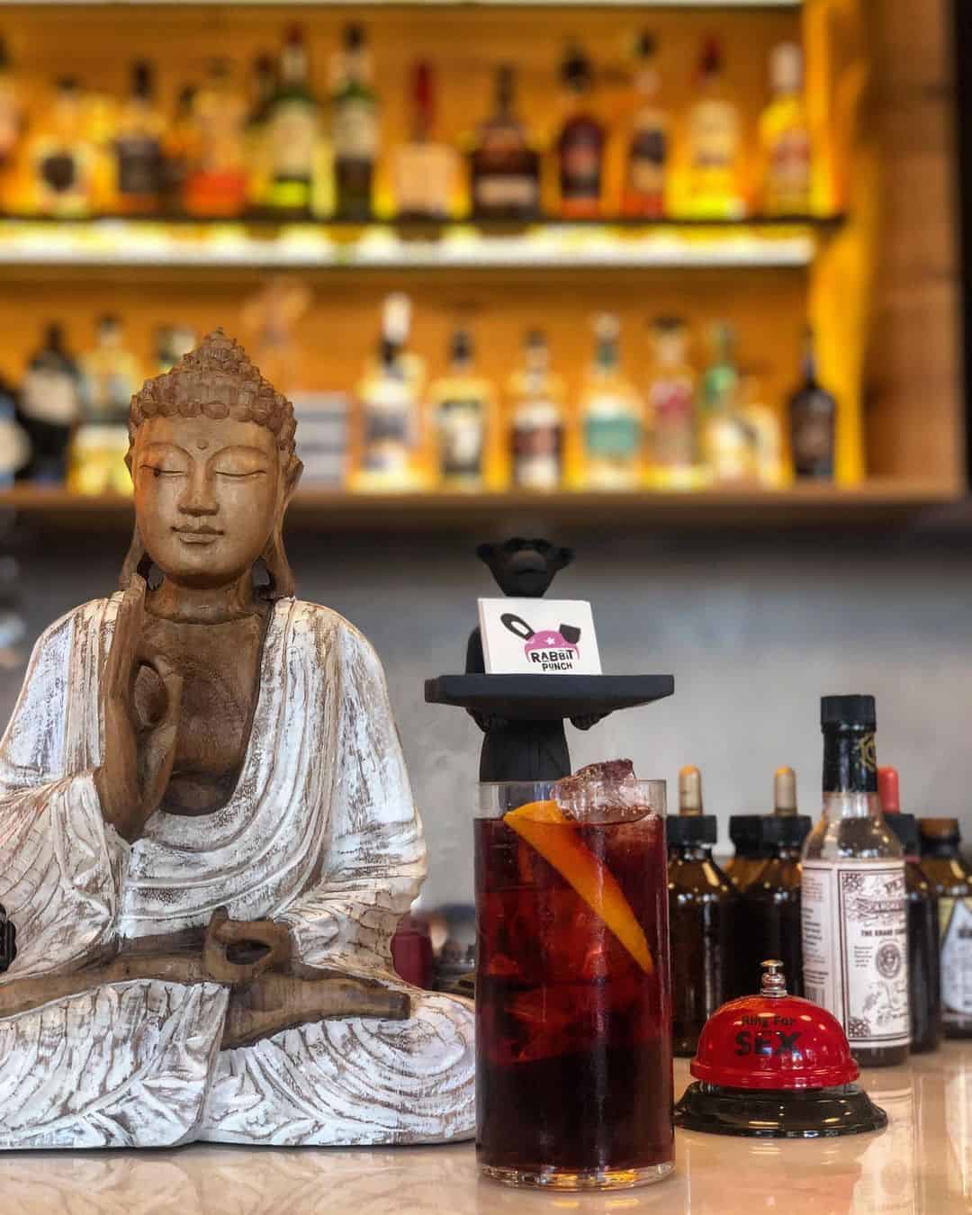 A serene Buddha statue rests on a counter beside a refreshing drink