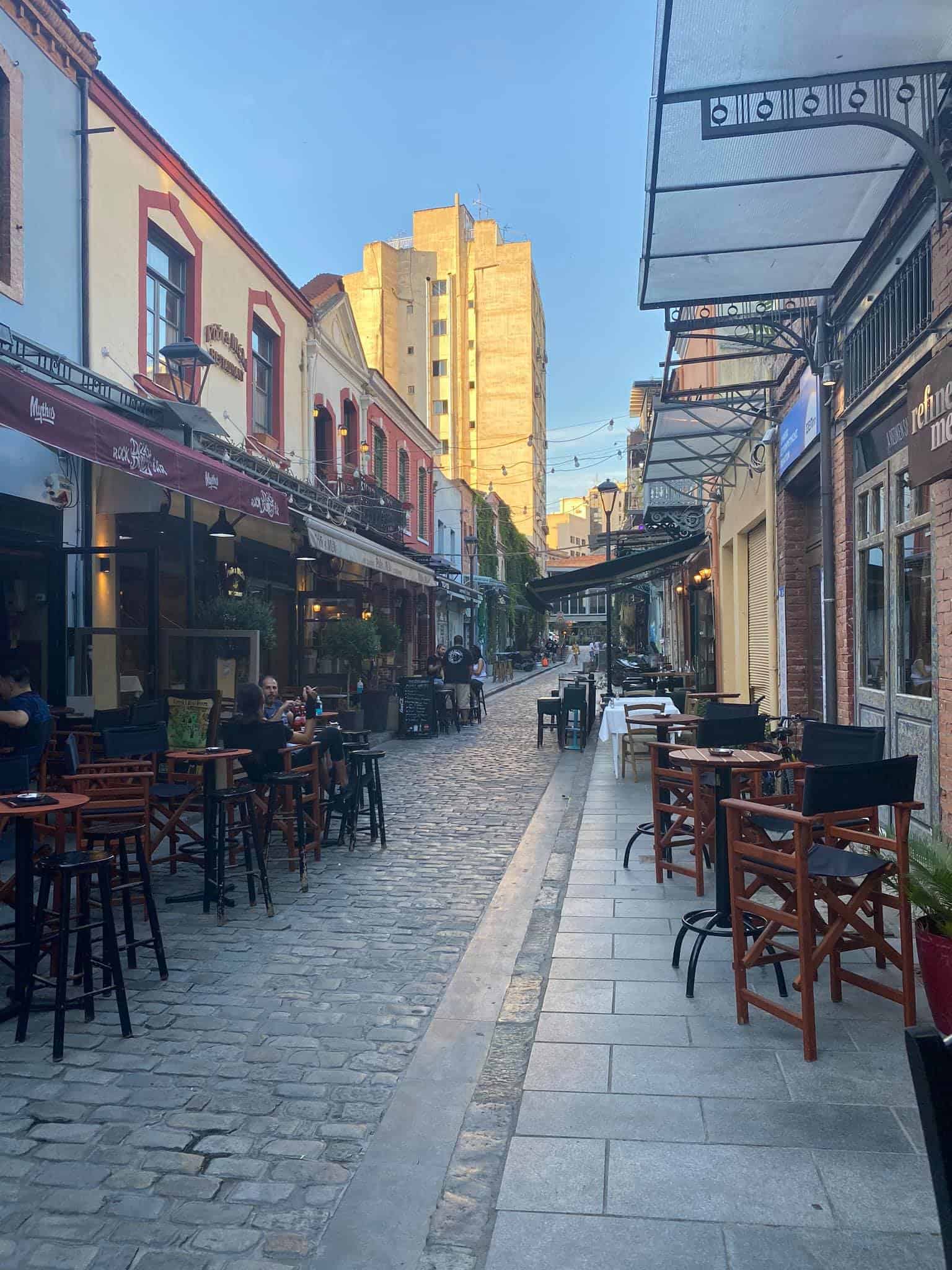 A bustling city street featuring outdoor tables and chairs