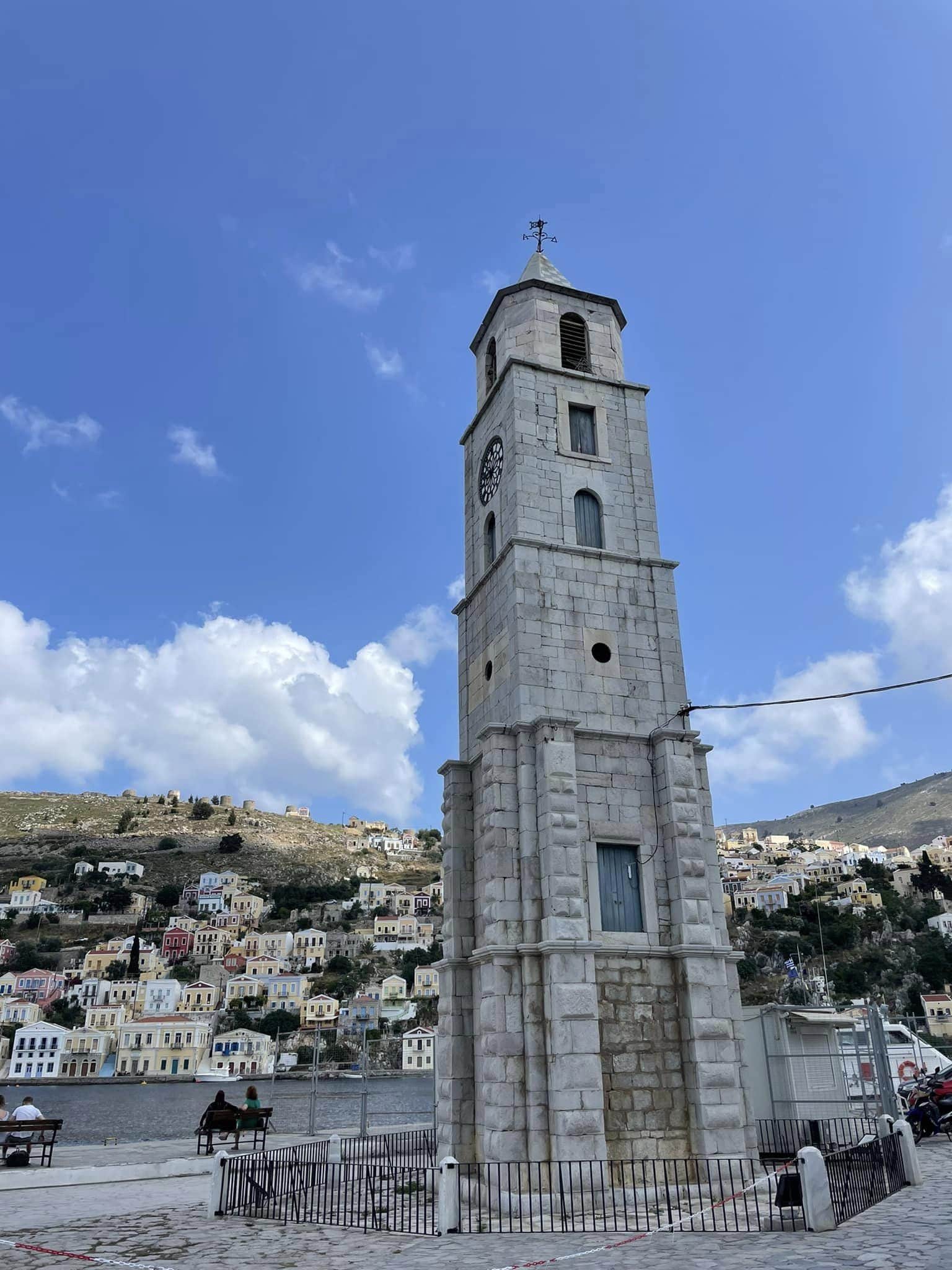 A clock tower stands prominently in the center of a bustling town