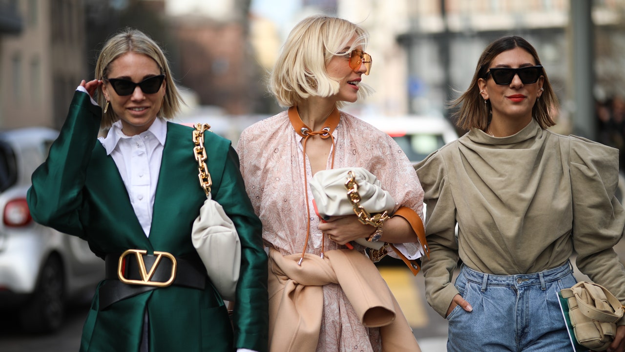 Three women walk along the street, displaying diverse fashion choices in their distinct outfits