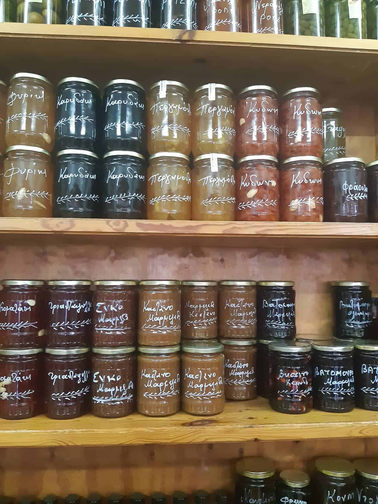 A shelf displaying an assortment of jars filled with various types of colorful jams