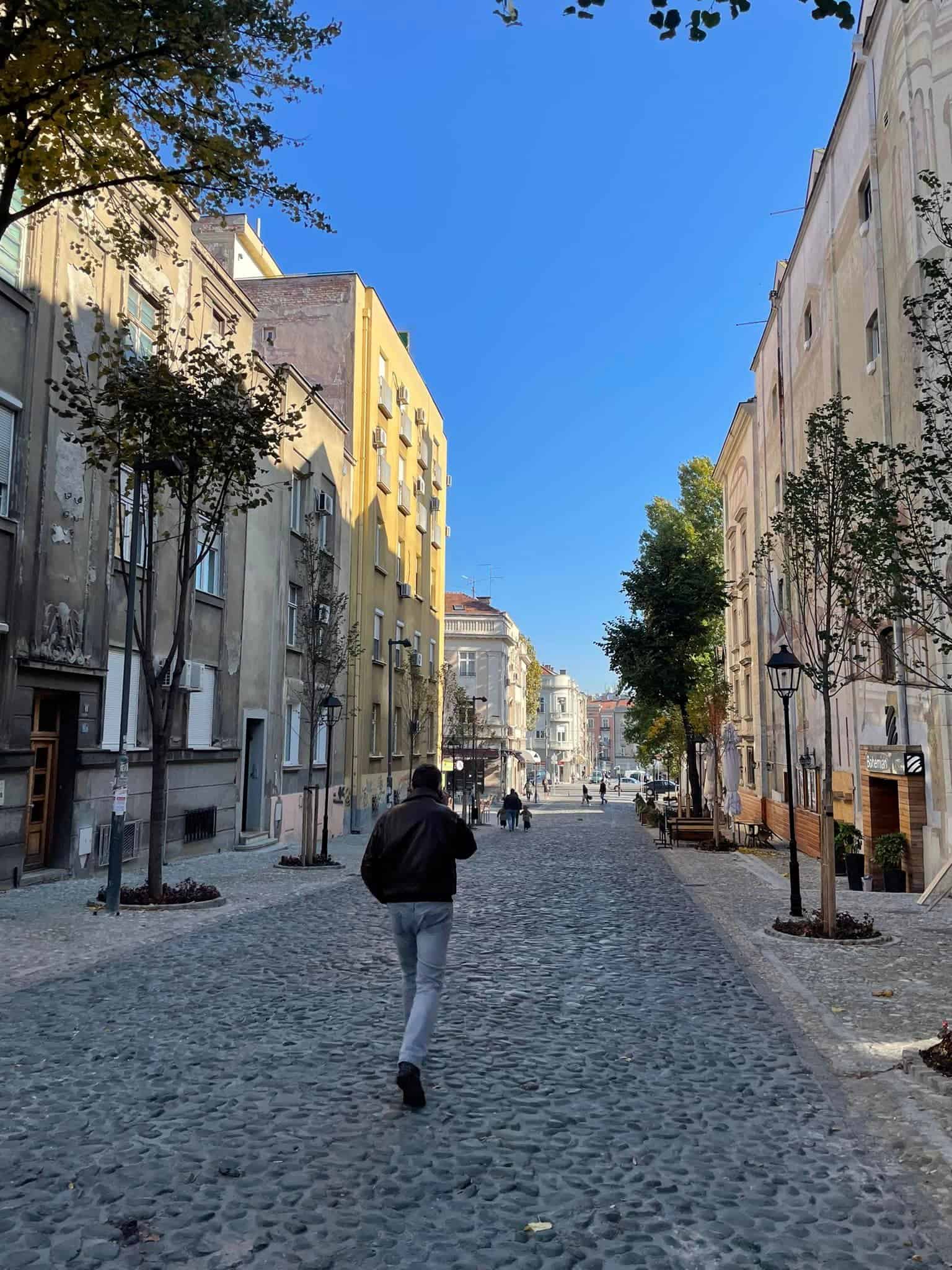 A man walks leisurely on a cobblestone street