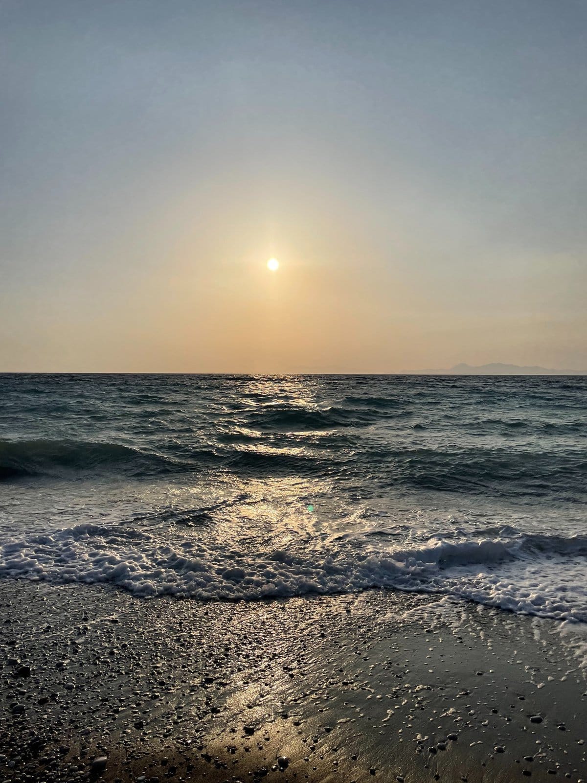 A serene sunset casts warm hues over the ocean