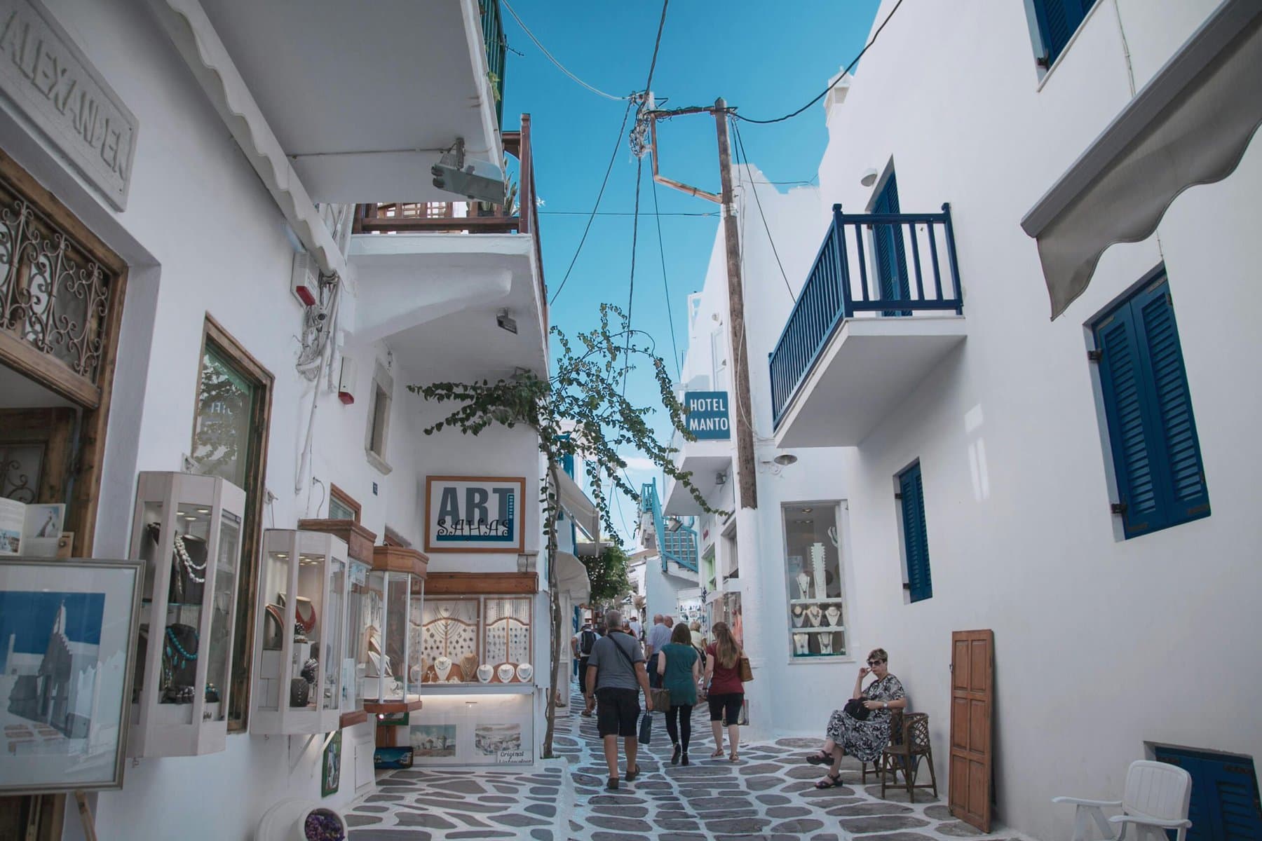 A picturesque scene of people strolling along a narrow street in a charming Greek village