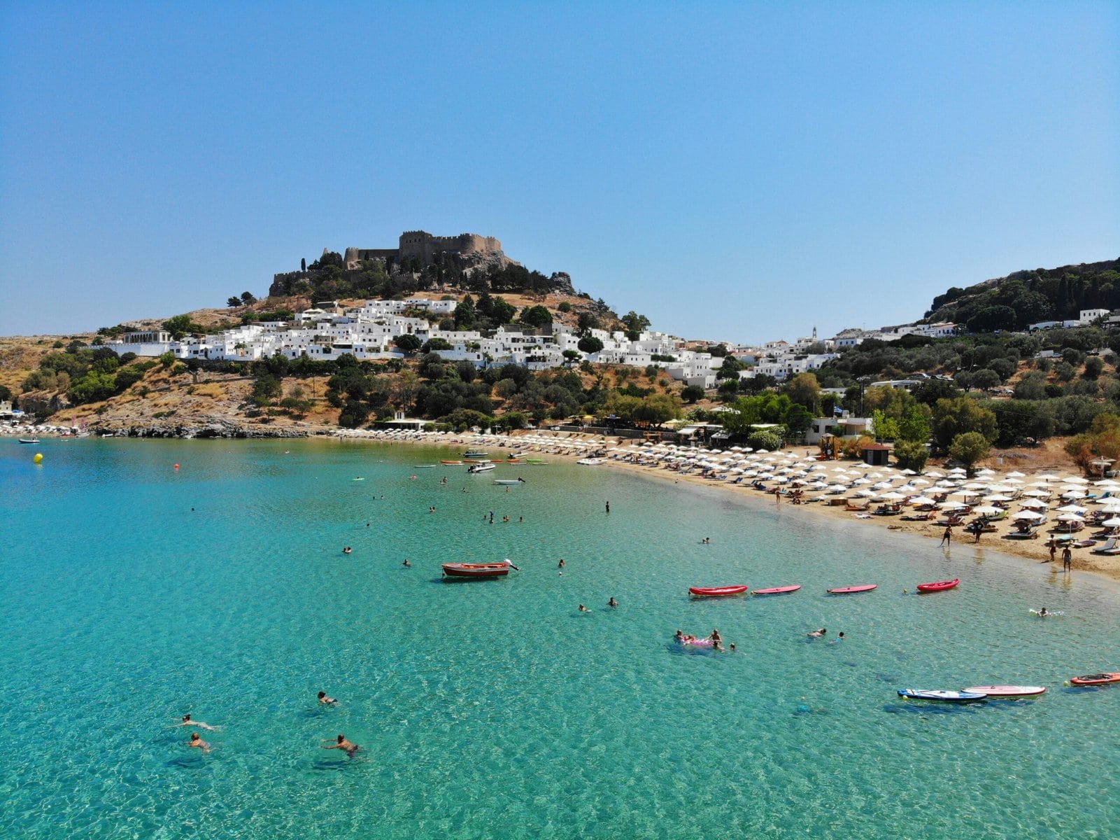 A vibrant beach scene filled with people swimming and sunbathing under the sun