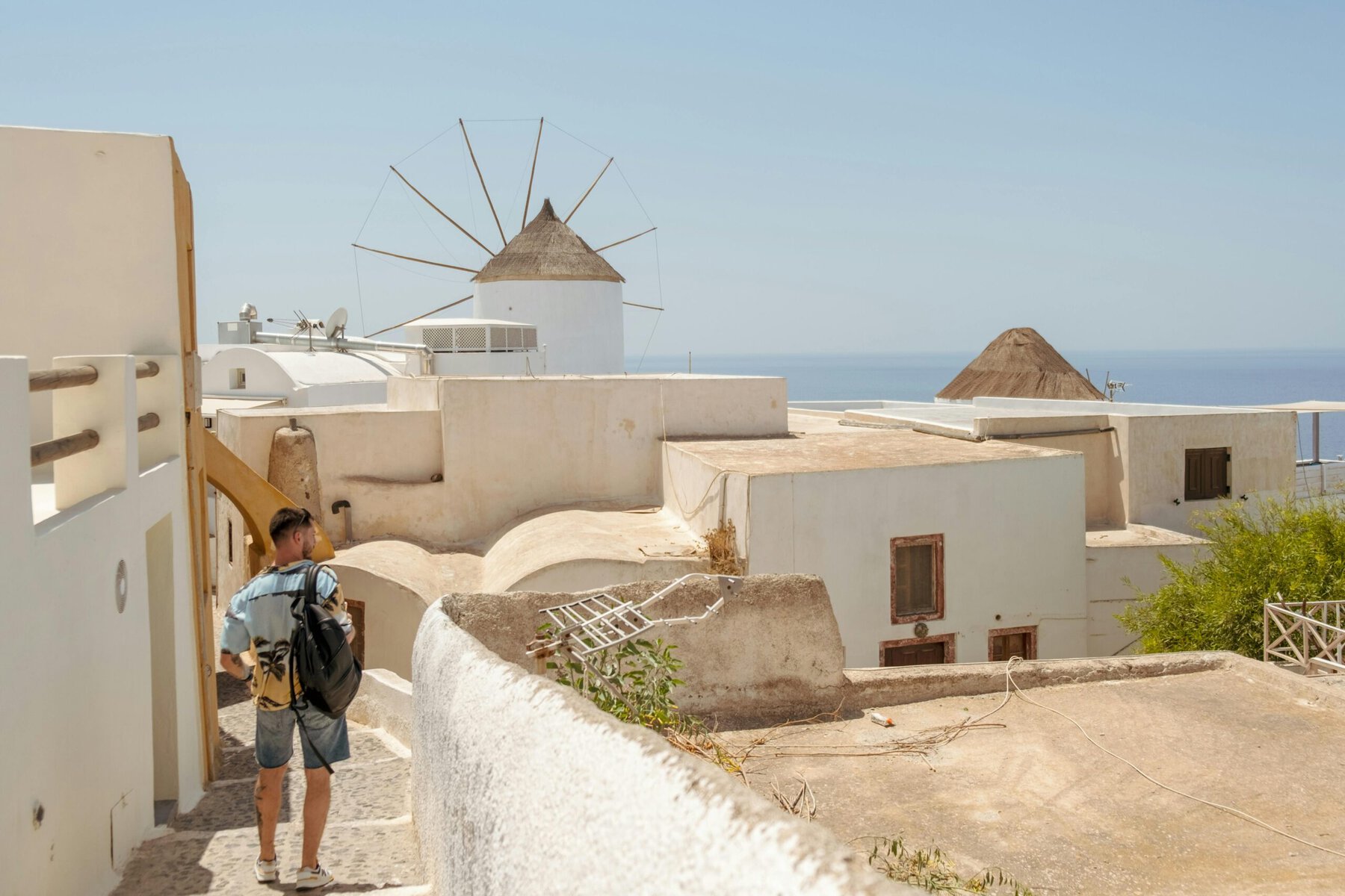 A man carrying a backpack walks along a narrow path surrounded by greenery