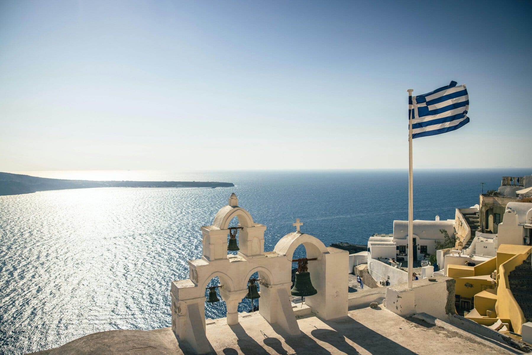 Greek flag waving atop a traditional church in Oia, Santorini