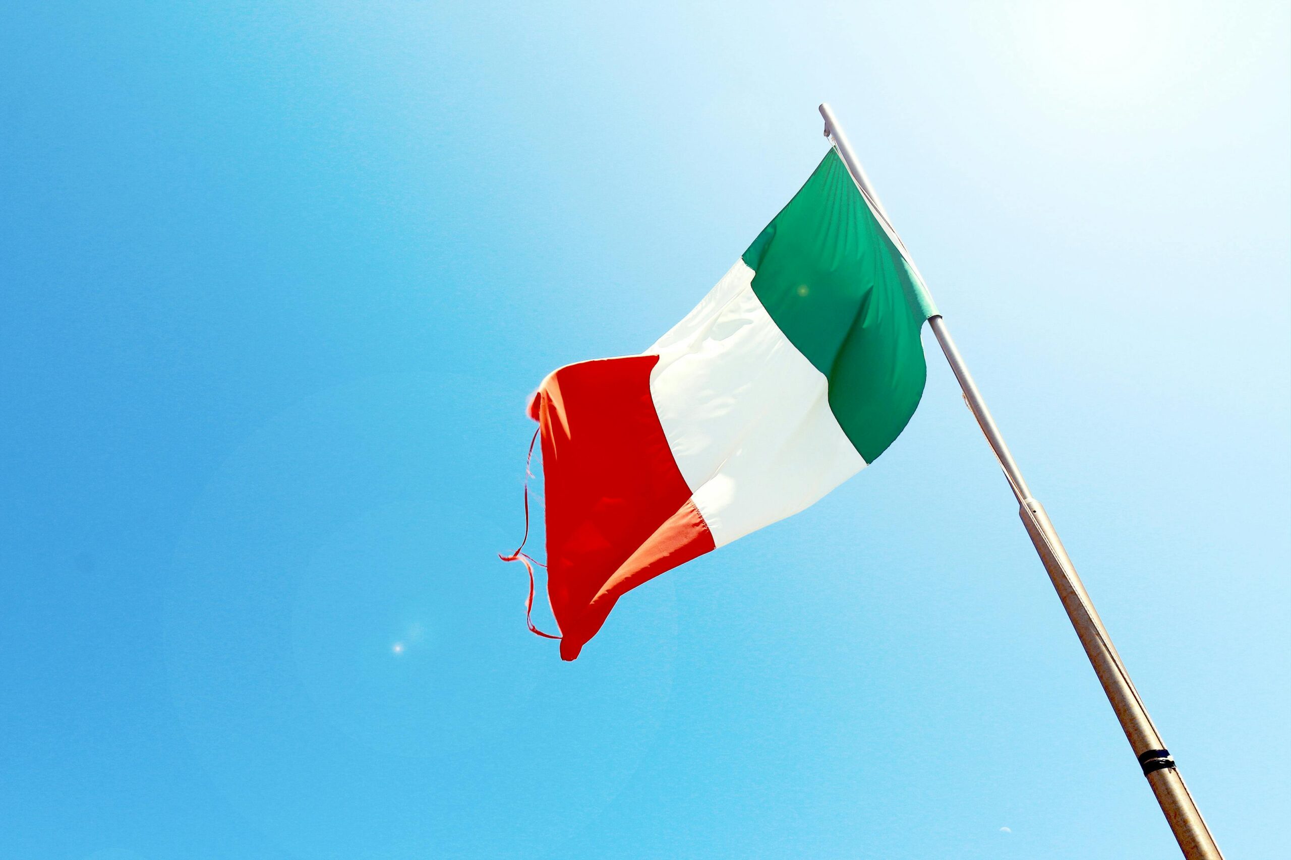 An Italian flag proudly displayed on a pole against a clear blue sky