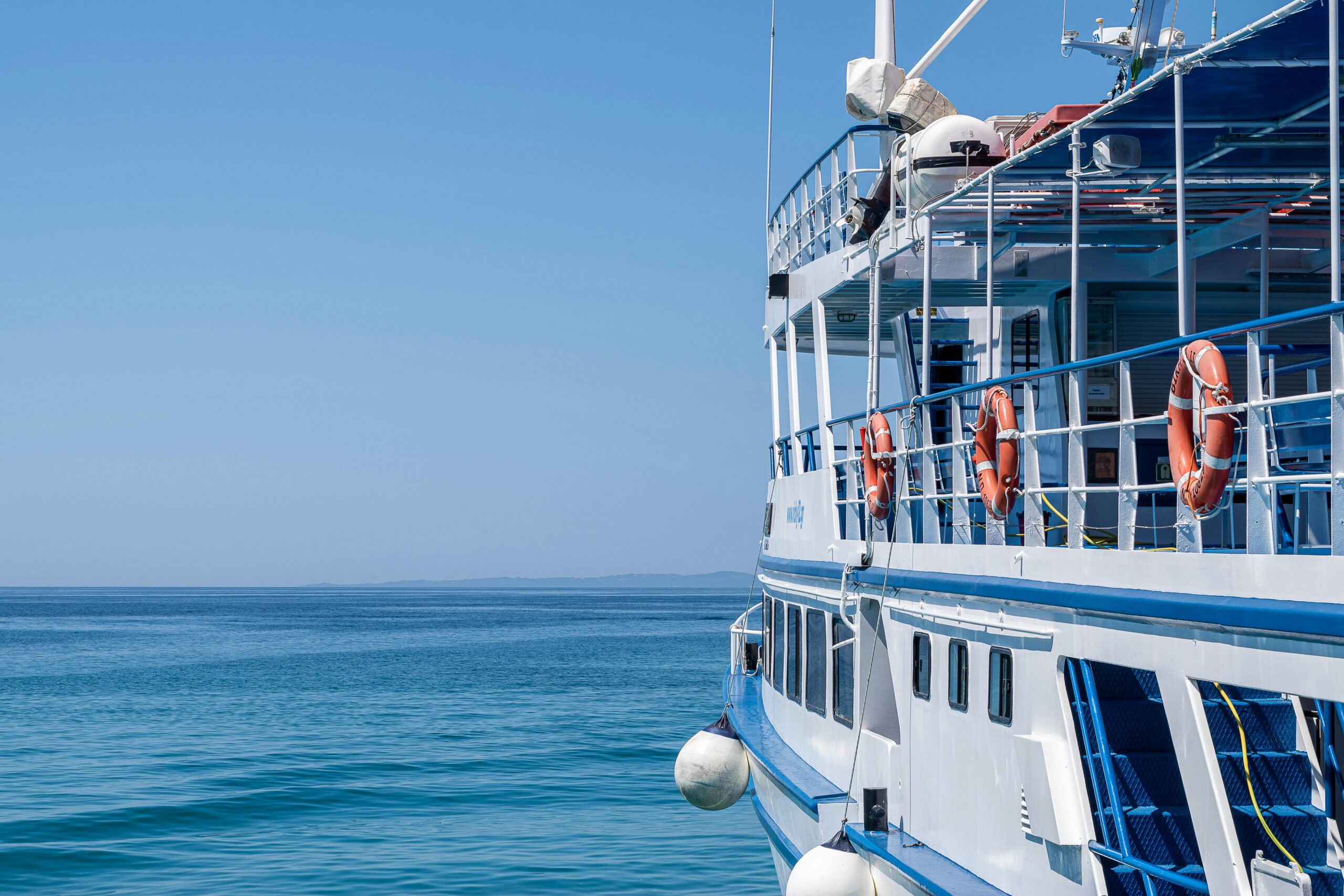 A blue and white boat gently floating on calm waters under a clear sky