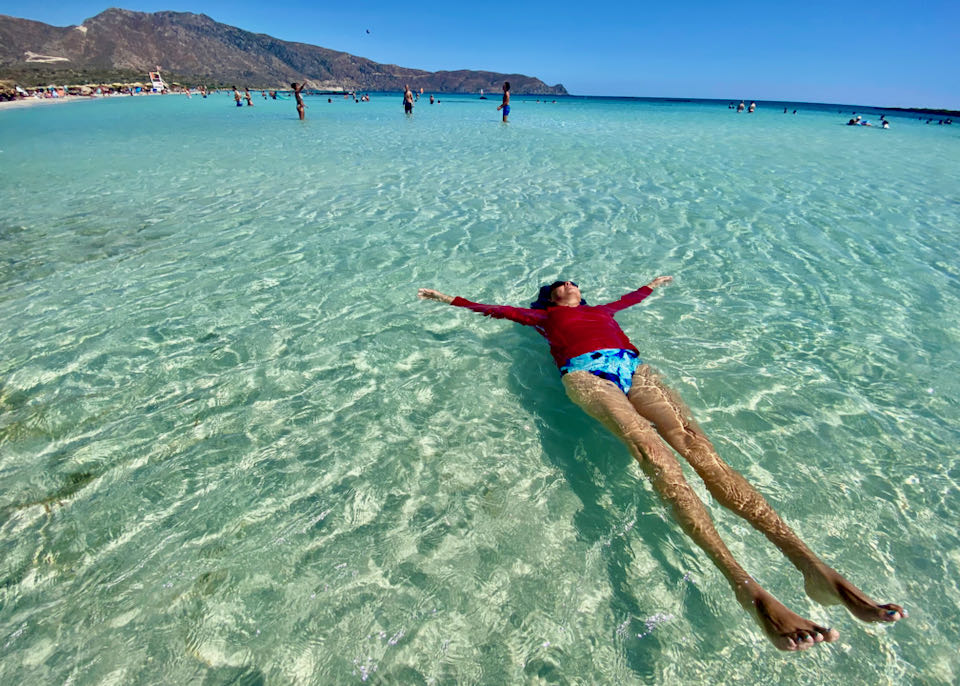 A woman relaxes in the clear water at a serene beach