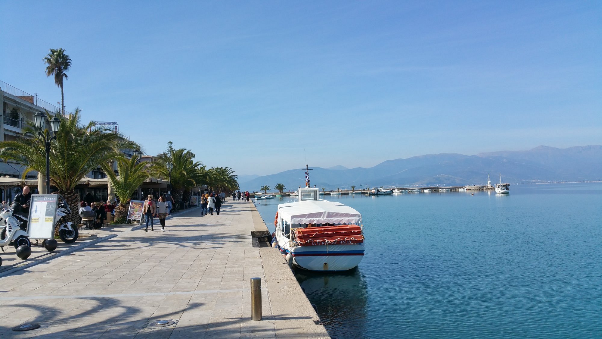 A boat is securely docked on the water beside a wooden pier, reflecting the serene surroundings