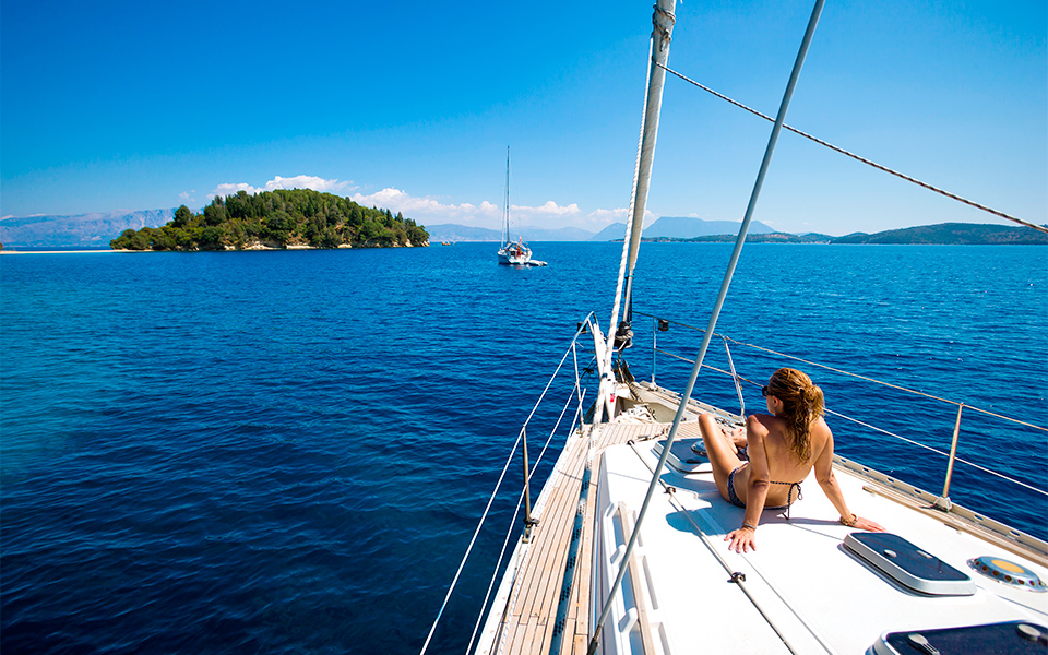 A woman seated gracefully on the bow of a sailboat