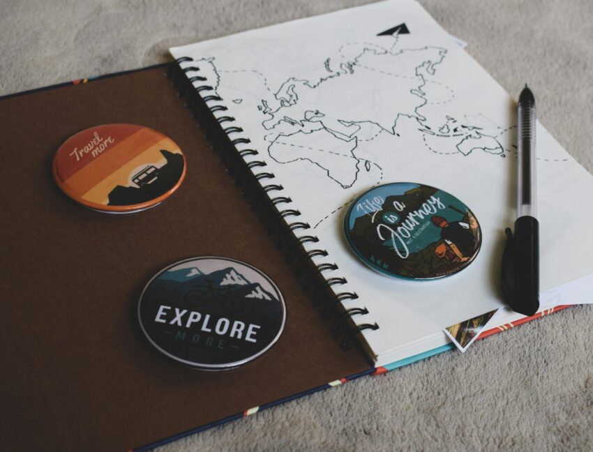 A journal with a drawing of a map and travel-themed pins.