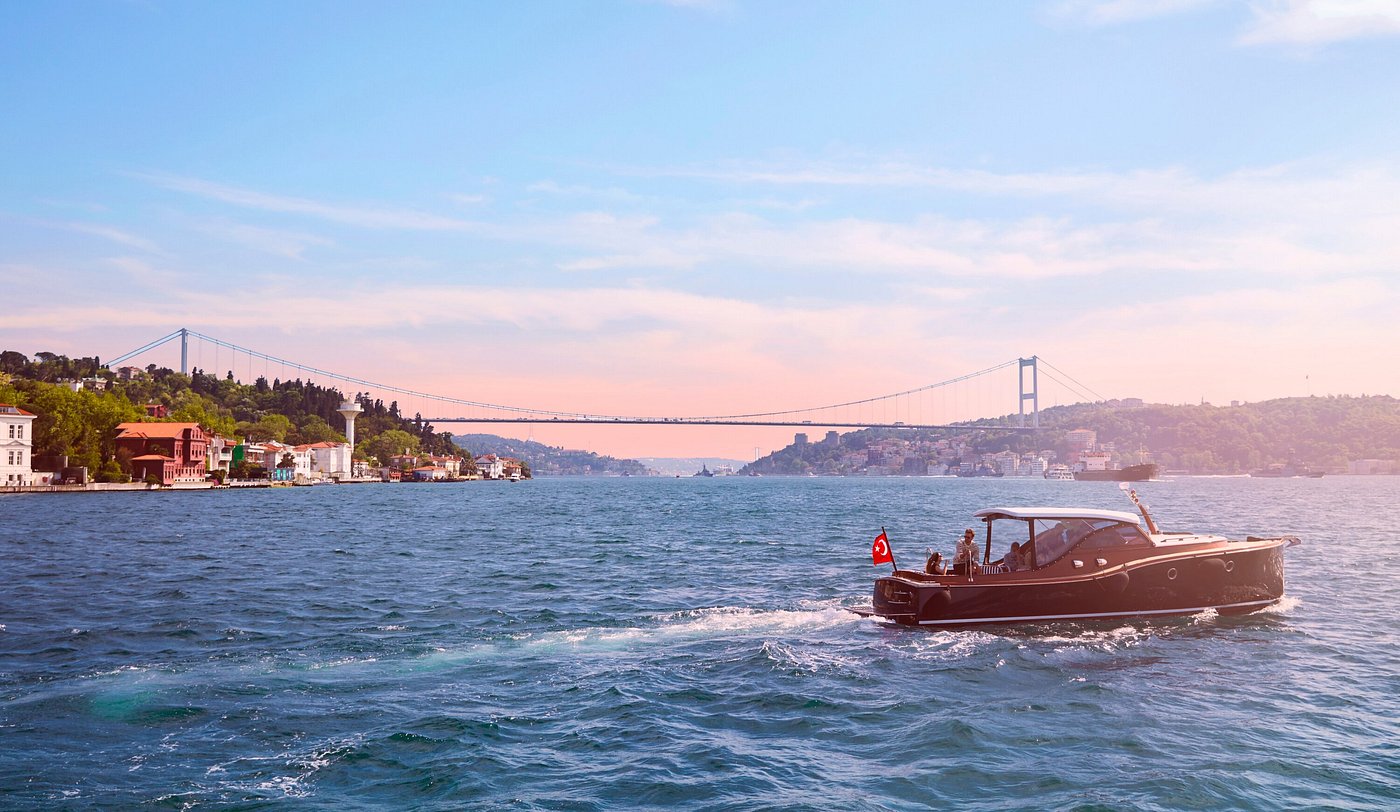 A boat glides across the water, approaching a bridge in the background, showcasing a serene landscape