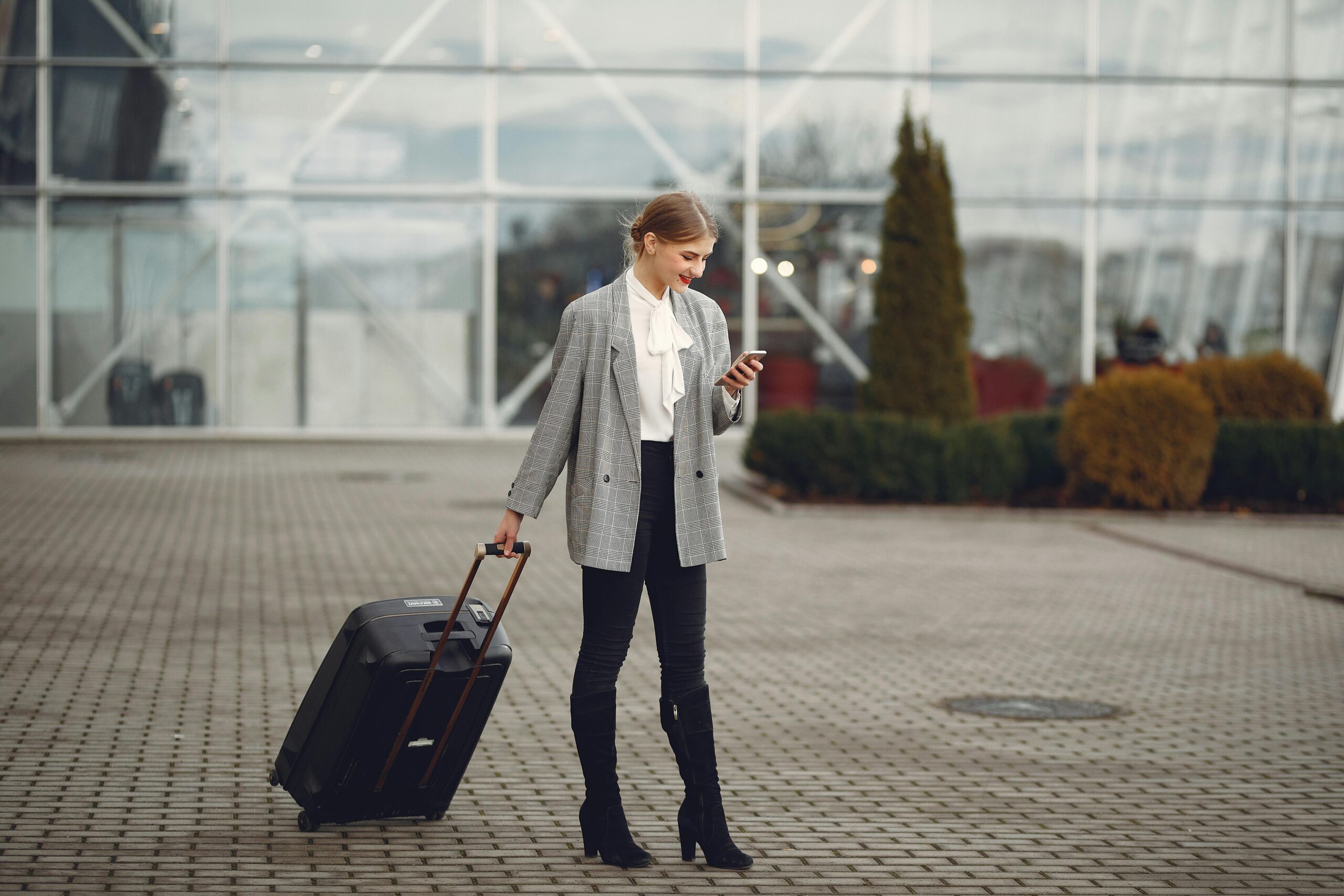 a woman holding a suitcase and looking at her phone