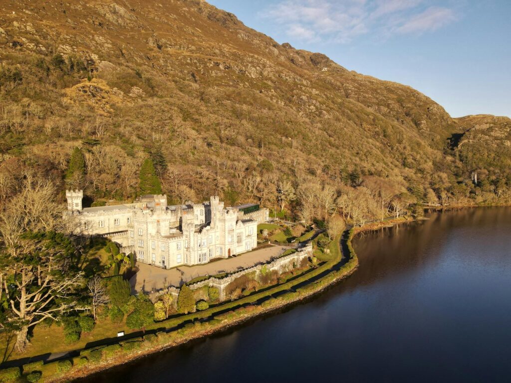 A serene view of Kylemore Abbey reflecting on a tranquil lake, surrounded by rugged Irish mountains