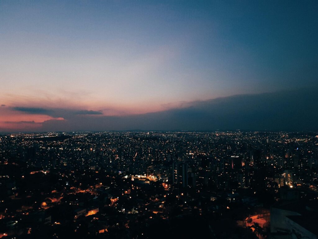 Dusk view of Belo Horizonte's skyline with glowing city lights and a colorful sunset, showcasing the vibrant urban landscape.