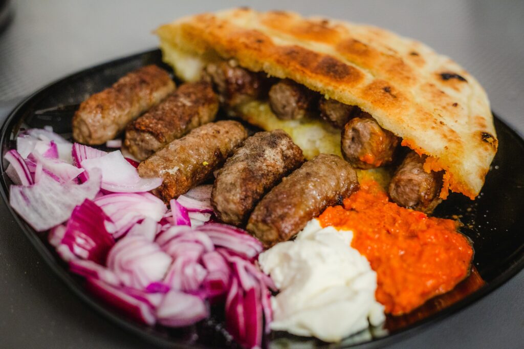 Grilled Bosnian ćevapi served with flatbread and onions, showcasing traditional Balkan cuisine