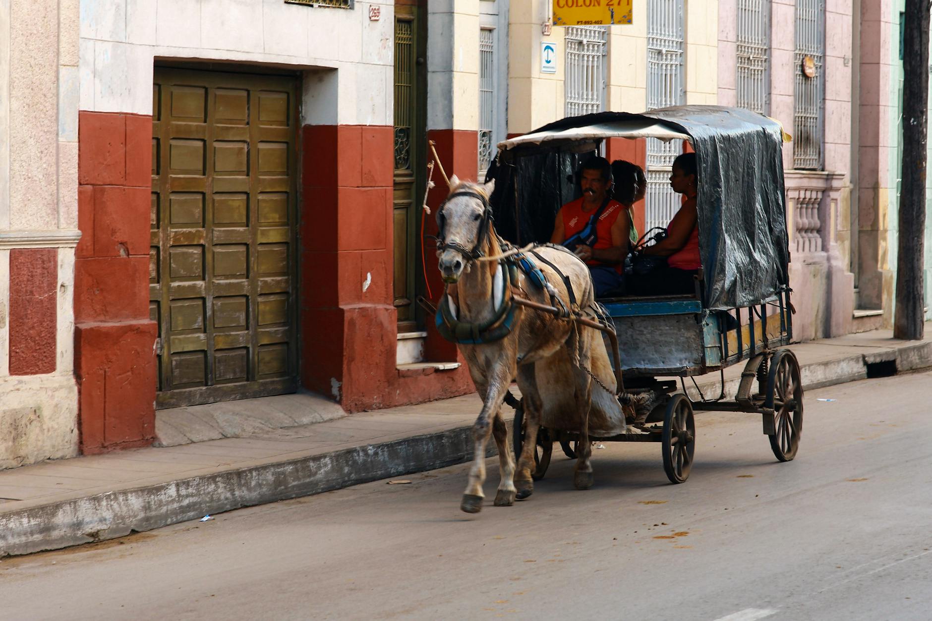 Horse pulling a cart with passengers along a cobblestone street in a charming, slow travel-inspired town