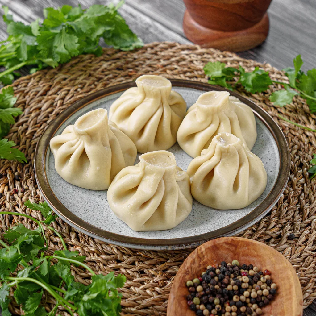 Plate of Georgian khinkali dumplings garnished with fresh herbs, highlighting traditional Eastern European cuisine and authentic handmade soup dumplings