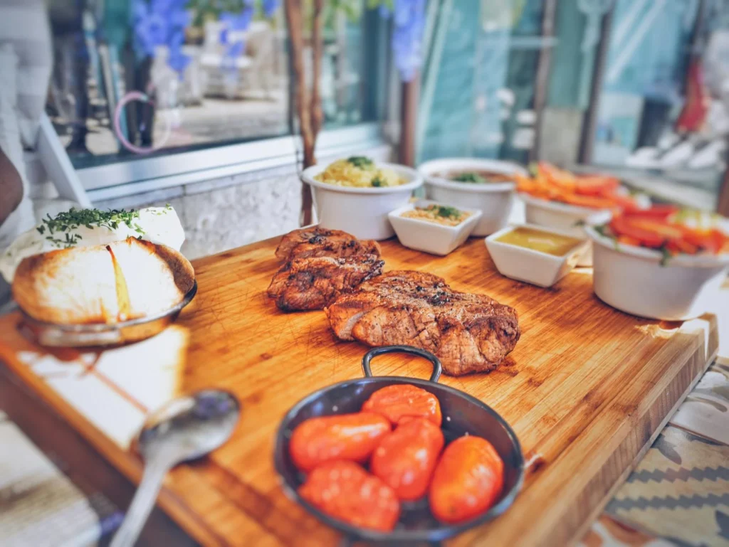 Rustic Portuguese meal featuring juicy beef, fresh vegetables, and a homemade aesthetic on a wooden table setting