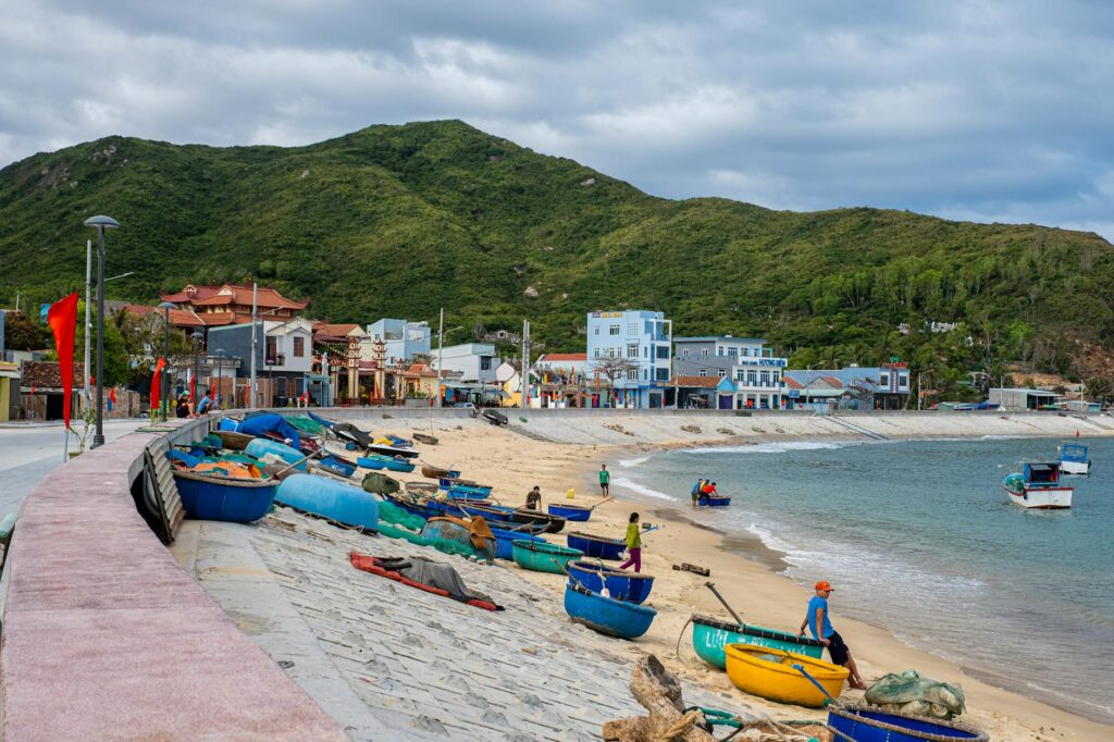 a beach belonging to a small seaside town with colorful boats docked in it