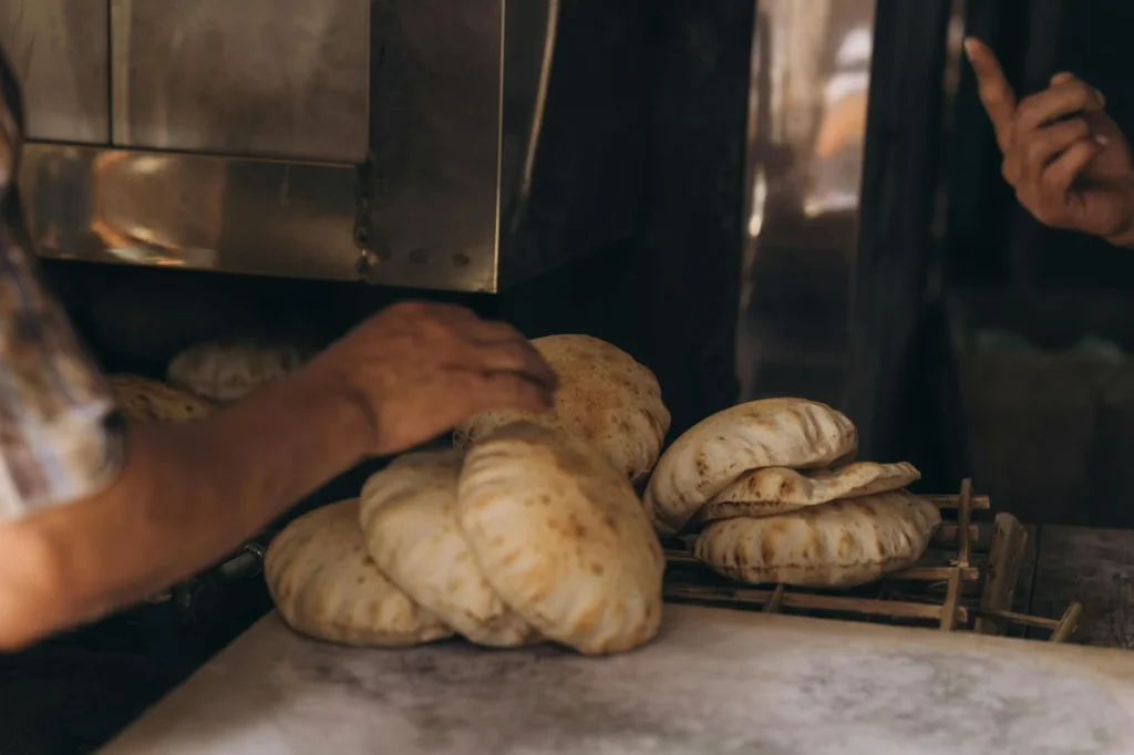 close-up of hands kneading dough to make traditional Egyptian bread in a rustic Alexandria bakery.