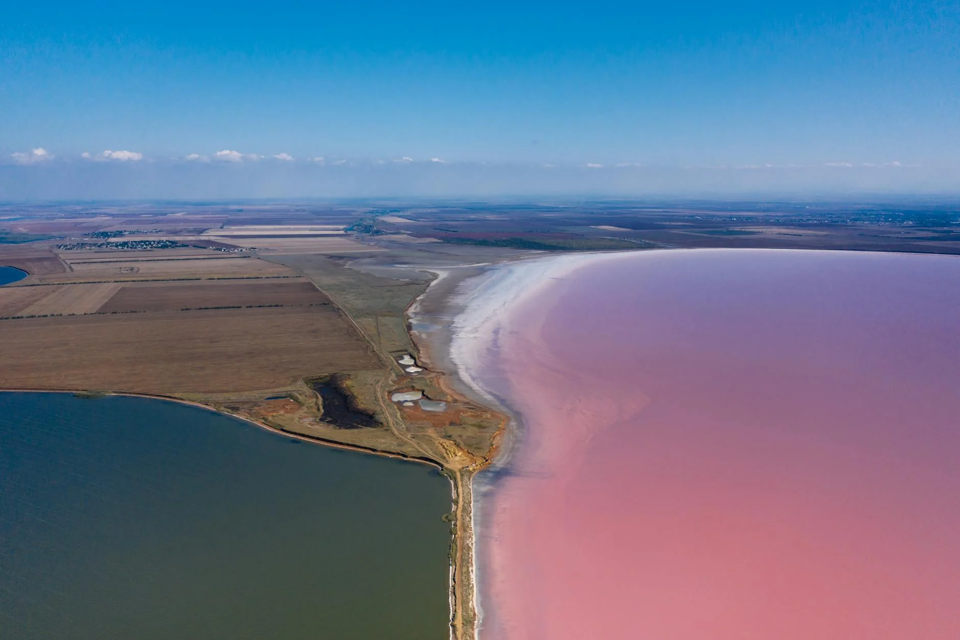 A breathtaking aerial shot of Sasyk salt lake with pink hues, showcasing the rural landscape in Crimea, Ukraine.