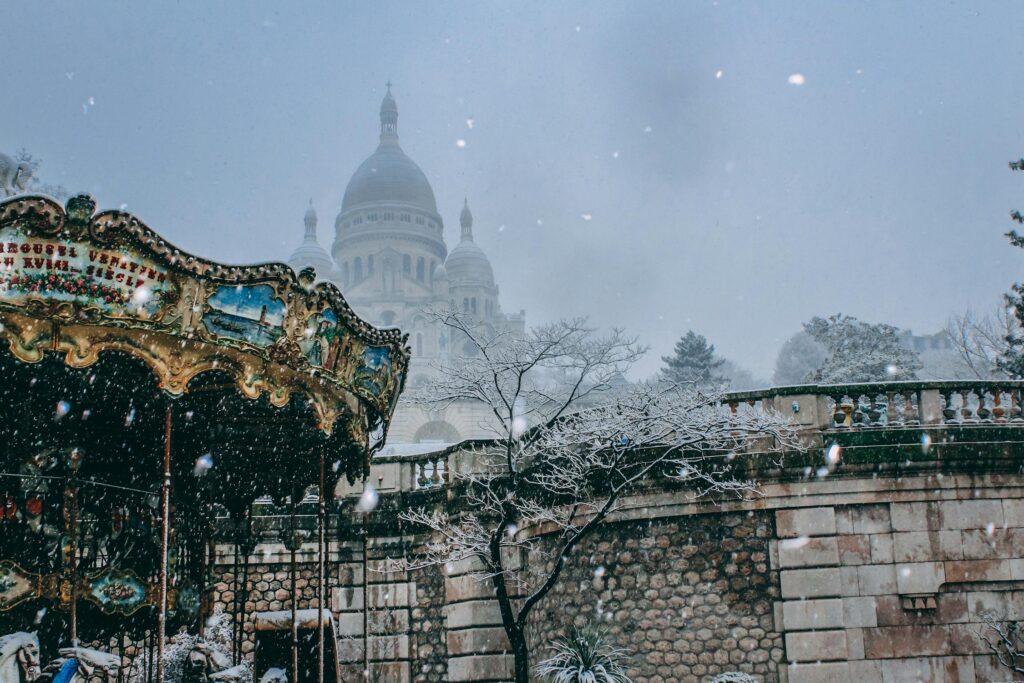 A captivating winter scene featuring a carousel with the Sacré-Cœur Basilica in the backdrop of snowy Montmartre, Paris.