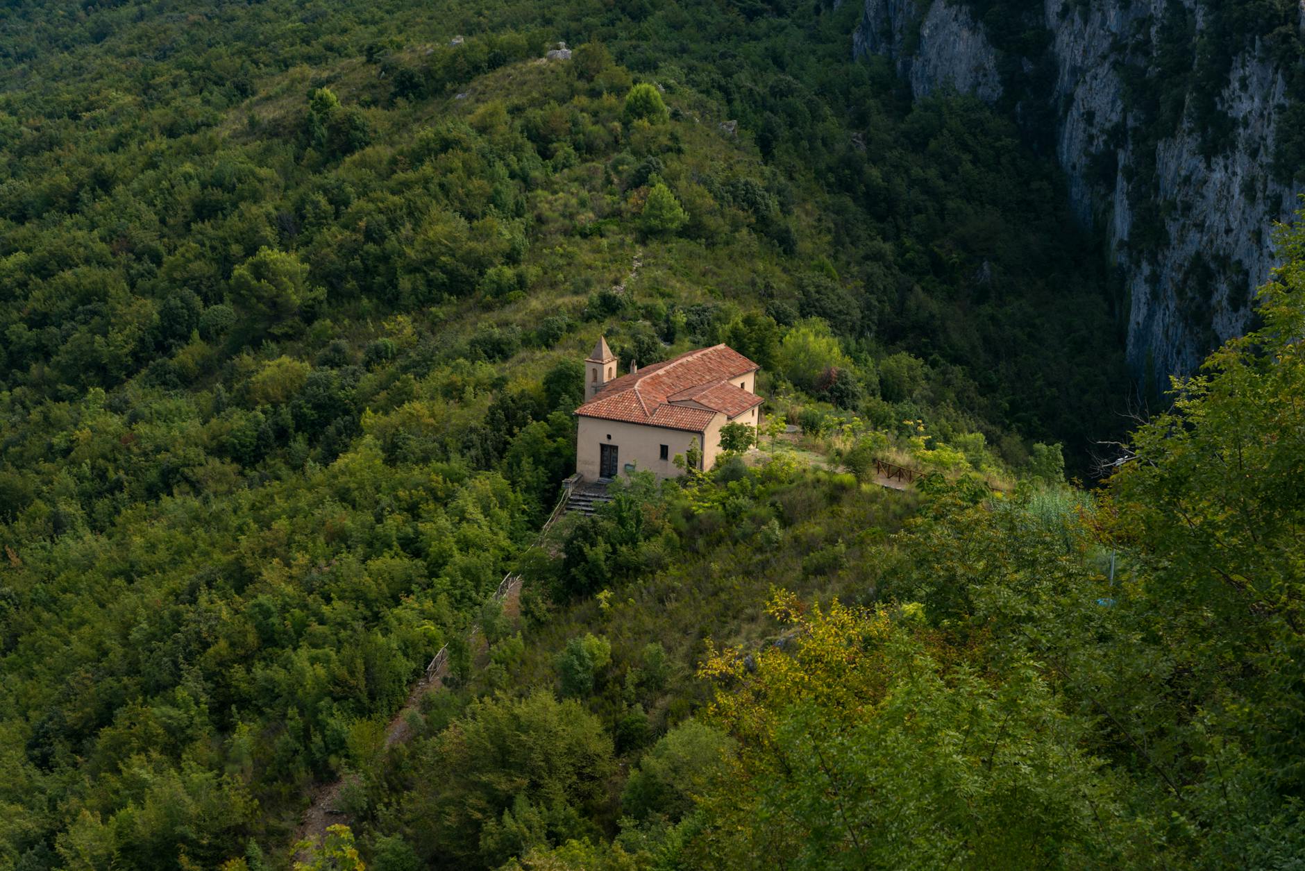 Aerial view of a secluded church nestled in lush Maratea, Basilicata landscape.