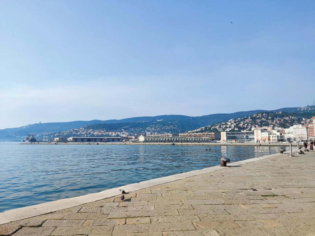 Beautiful view of the harbor and coastline in Trieste, Italy, with clear sky.