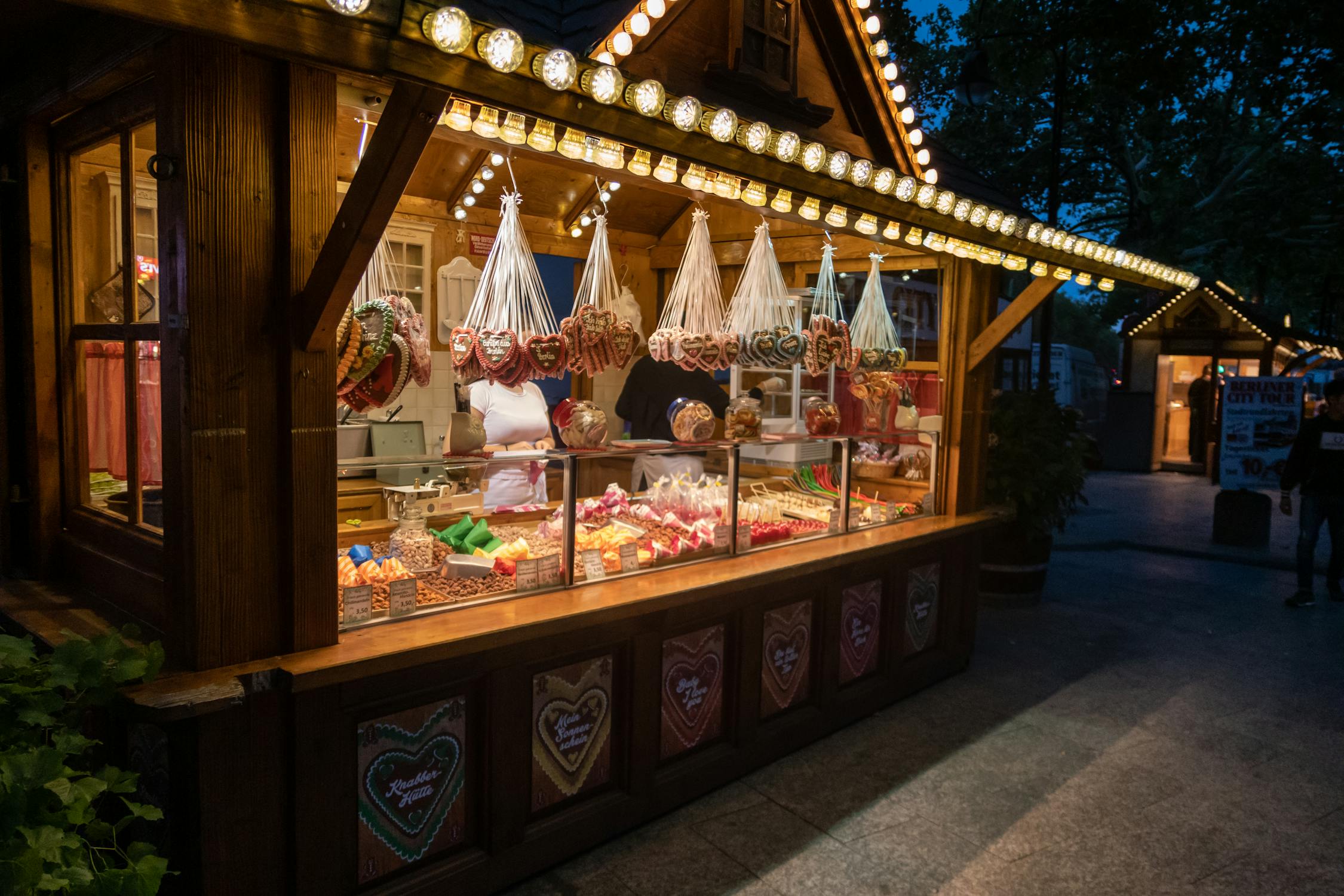 Explore Berlin's vibrant night market with a cozy sweets stall, offering traditional treats and festive lights.