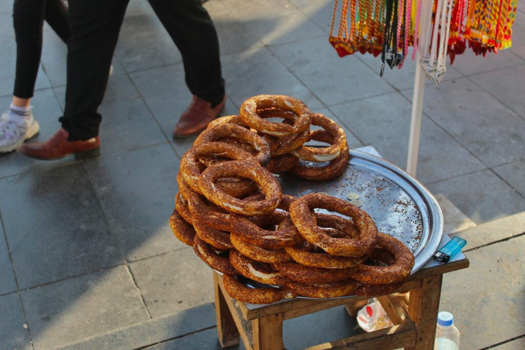 Freshly baked simit on a street vendor's tray in a bustling Turkish city.