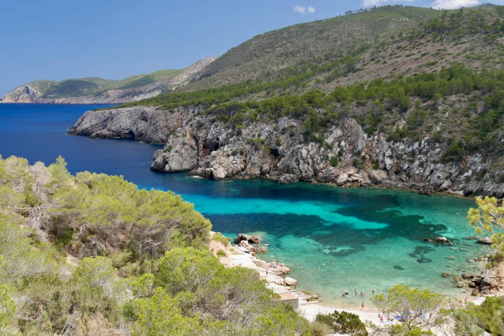 Pristine turquoise waters and rocky coastline of a secluded Ibiza beach, perfect for summer adventures.