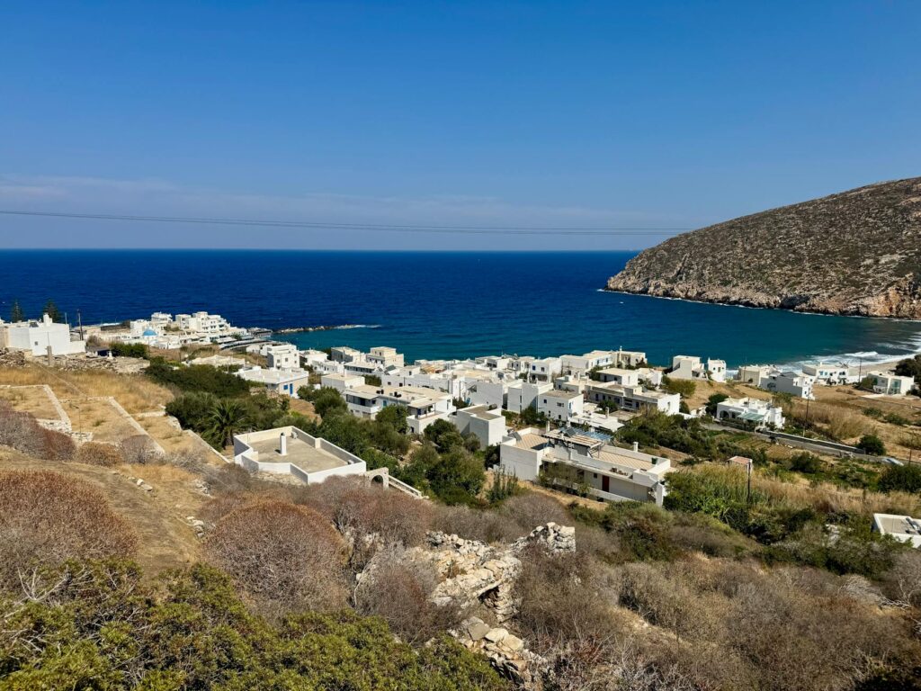 Stunning view of a Cycladic village by the sea with blue waters and white buildings.