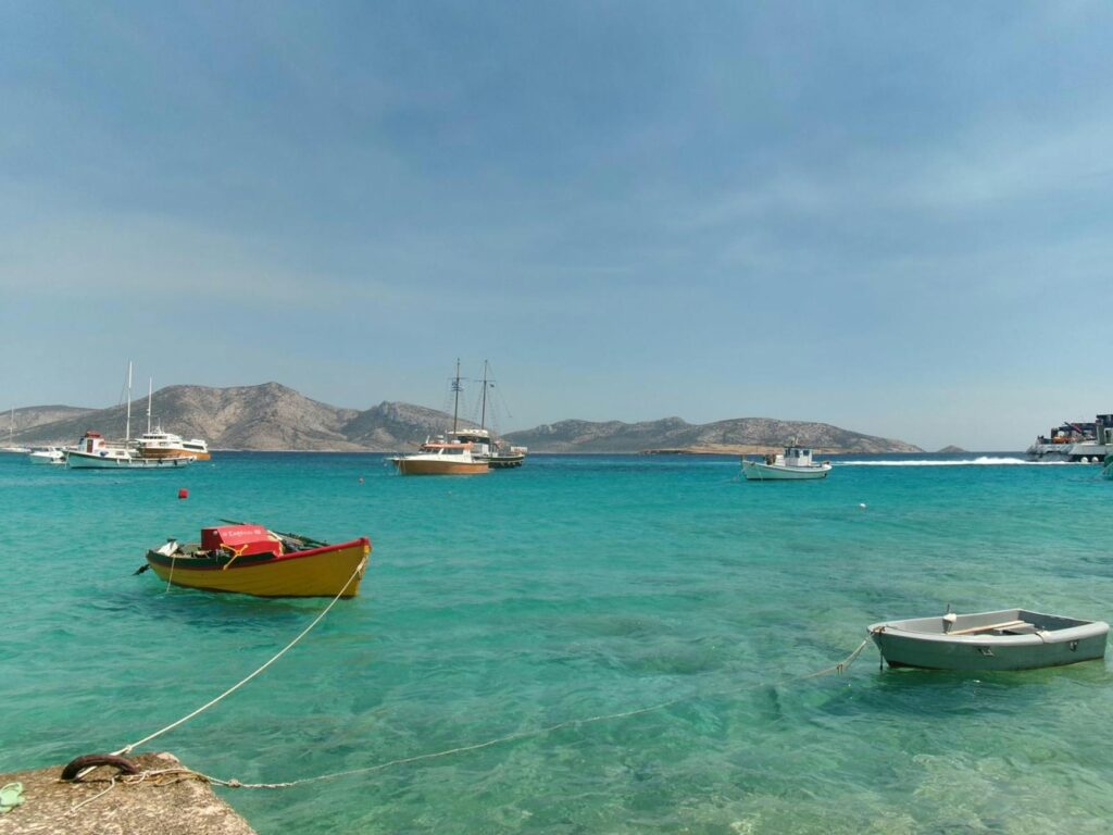 Tranquil boats on the turquoise waters of Milos, Greece, under a clear summer sky.