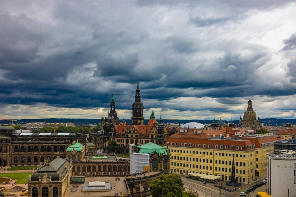 View of Dresden's historic architecture under dramatic cloudy skies. Features famous landmarks.